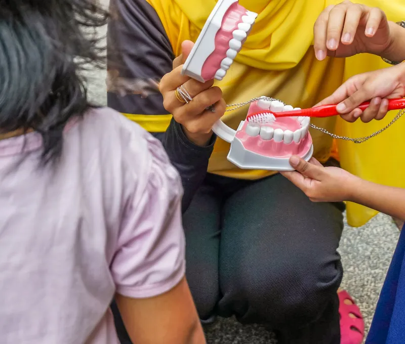 Female instructor holding out a teeth replica teaching kids