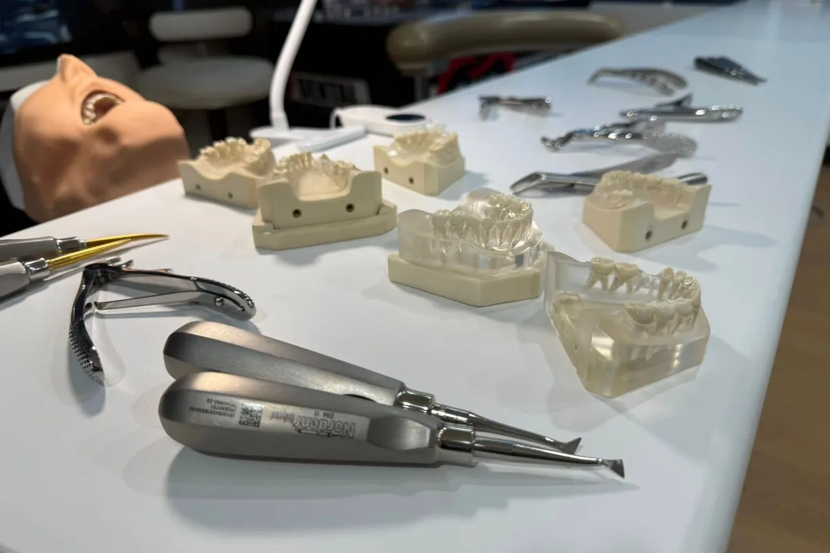 Dental lab table with tooth models and assorted instruments laid out (pliers, scalers, mirrors).