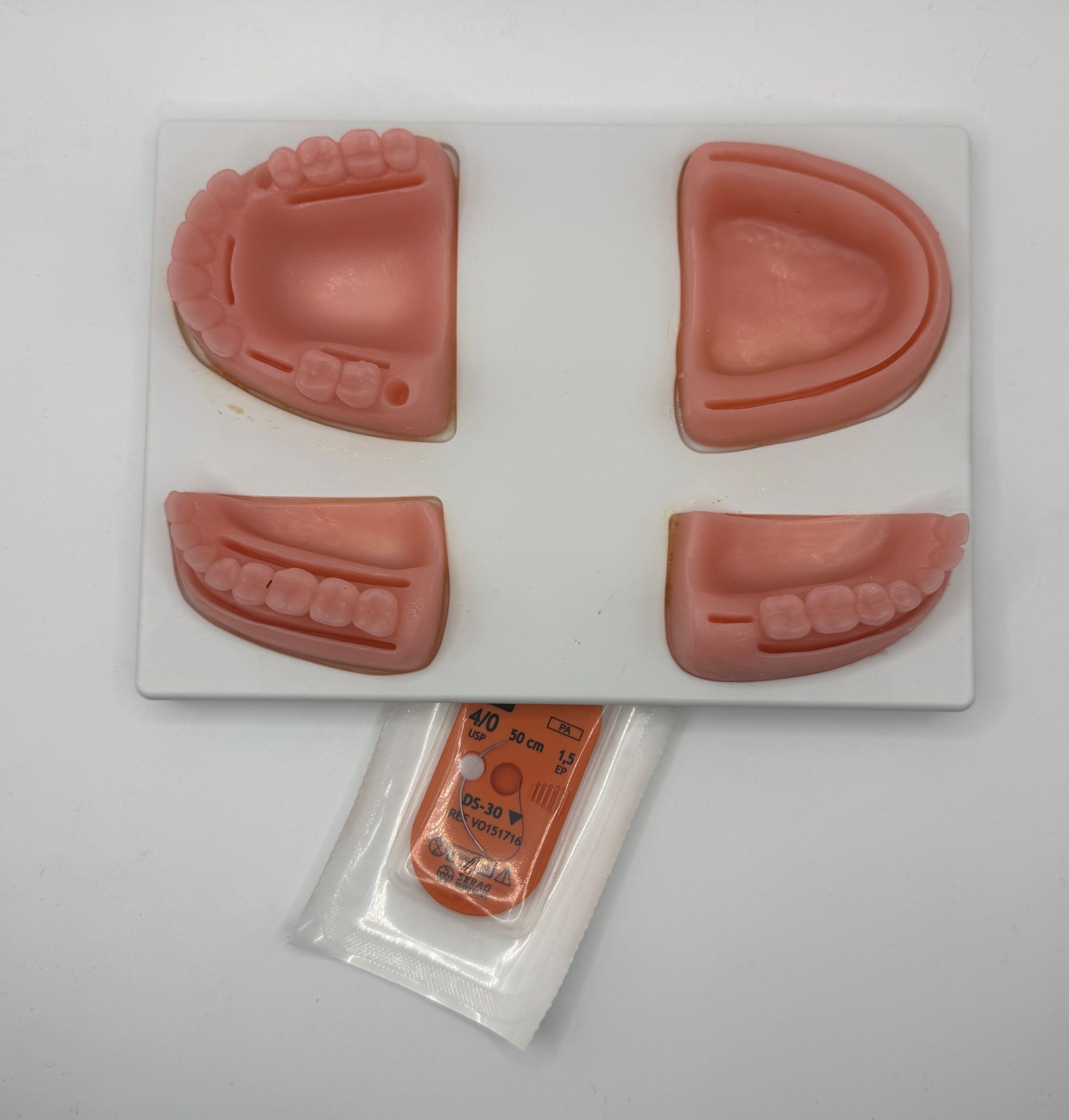 Dental impression trays with pink silicone blocks showing upper and lower tooth molds on a white surface.