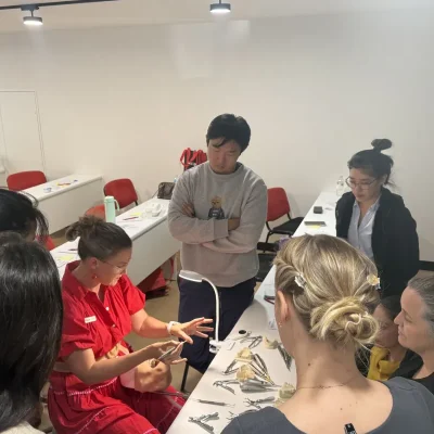 Dental students gathered around an instructor during a hands-on training session